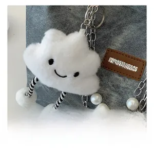 Macro view of cloud plush charm with pearl chain on a denim tote bag detail