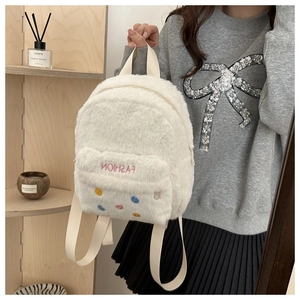 Macro detail of soft white faux fur backpack with pink embroidery and colorful dots
