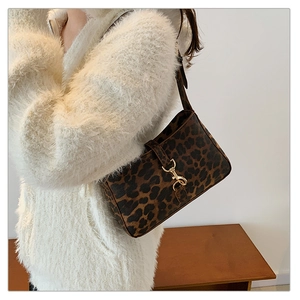 Detail of leopard print shoulder bag with gold metal buckle on white sweater