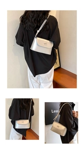 Detail of silver flap bag with metallic bow ornament and slim shoulder strap