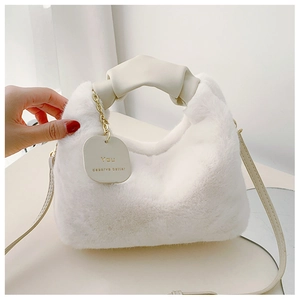 Détail du sac en peluche blanche avec poignée en cuir nouée et médaillon doré