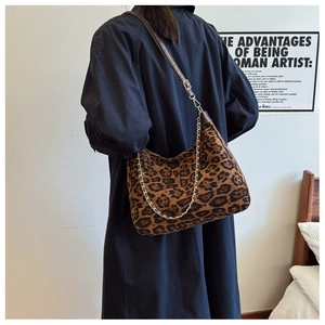 Detail of leopard print canvas bag with brown leather strap and gold chain accent