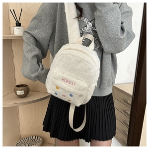 Detailed close-up of a white plush backpack with pink 'FASHION' embroidery on soft fur