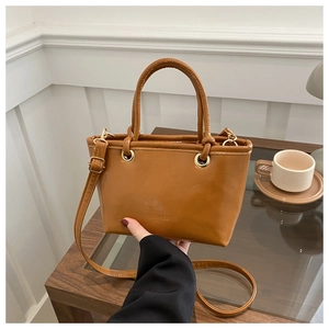 Detail der braunen Eimer-Tasche mit Logo-Prägung und goldenen Metallbeschlägen