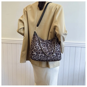 Detail of leopard print hobo bag with black leather strap and gold chain accent