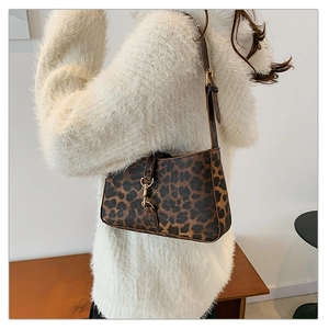 Detail of leopard print underarm bag with gold hardware worn on a plush white sweater
