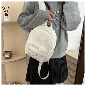 Close-up of white plush mini backpack featuring pink FASHION embroidery and colorful dots