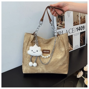 Detail of khaki canvas tote bag with chain strap, pearl pendant and fluffy charm