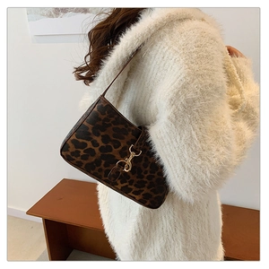 Close-up of leopard print baguette bag with gold metal buckle on white sweater