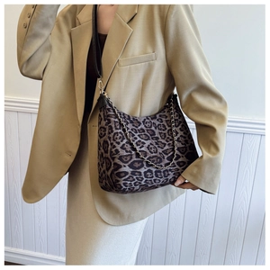 Detail of leopard print crossbody bag featuring gold chain and textured fabric material