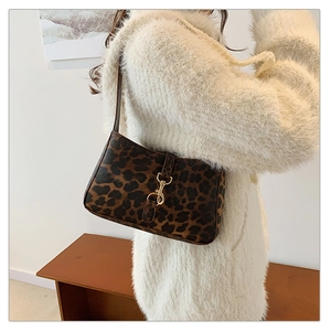 Detailed view of leopard print baguette bag with gold buckle and chain strap on a model