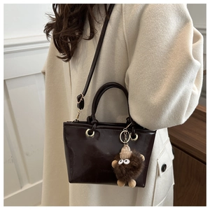 Close-up of chocolate brown bucket bag with tassel on wool coat