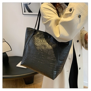 Detail of black crocodile texture tote bag with leather strap on a shoulder