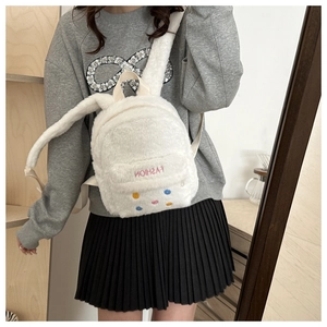Close-up of a mini white plush backpack with rabbit ears worn on a casual outfit