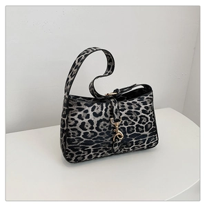 Detailed view of leopard print handbag featuring a premium golden metallic front clasp
