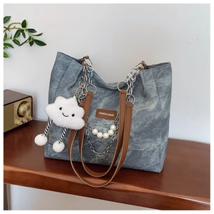Detail of gray canvas tote with silver chain, pearls and cute cloud charm on wood