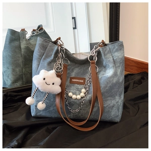 Detailed close-up of blue denim tote bag with pearl chain and plush cloud pendant