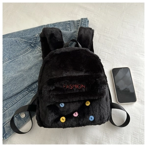 Detail of black plush backpack with FASHION embroidery and colorful button accents