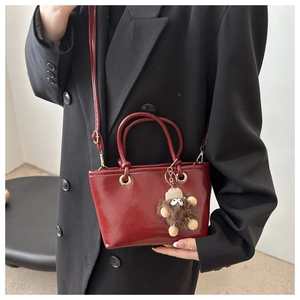 Red retro bucket bag in glossy PU leather with plush charm and fashion logo detail