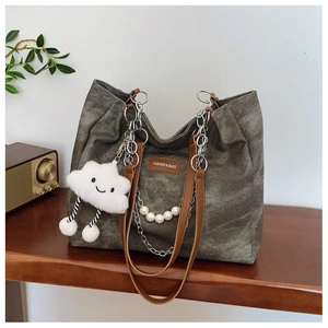 Detail of grey canvas tote bag with pearl chain, silver link, and cloud plush charm
