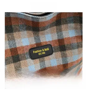 Macro view of blue-brown vintage plaid fabric and leather patch with stitching detail