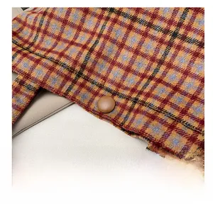 Macro shot of plaid wool fabric texture with stitching and a brown button detail