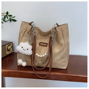 Detail of canvas tote with pearl chain, leather handles, and plush cloud charm