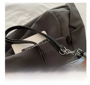 Detail of checkered tote bag featuring leather handle and silver metal chain link