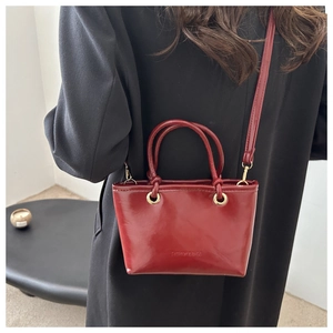 Modische rote Eimertasche aus glänzendem Leder als Umhängetasche für Damen getragen