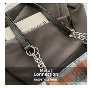 Detail of silver metal chain connecting the black leather handle to the checkered bag