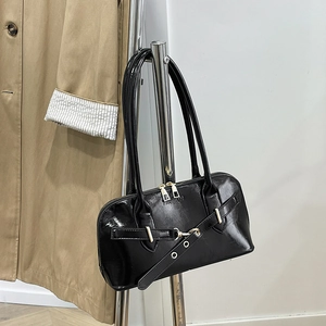 Close-up of black patent leather bag with buckle detail and FASHION embossed texture