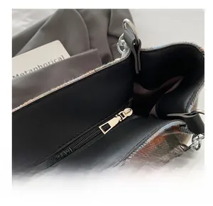 Detail of smooth gold zipper and black leather puller on a plaid tweed tote bag