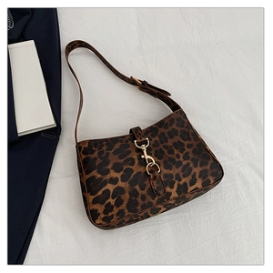 Close-up of leopard print shoulder bag with gold clasp hardware on white fabric