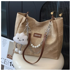 Close-up of khaki canvas tote bag with pearl chain and cloud plush pendant detail