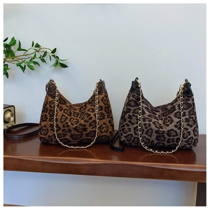 Detail of leopard print tote bags with metal chain straps on a wooden bench