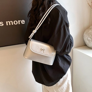 Sac bandoulière argenté métallisé avec nœud et double lanière porté par un modèle