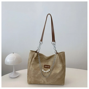 Detail of khaki canvas tote bag featuring decorative silver chain and white faux pearls