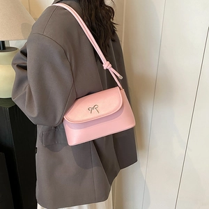 Sac à bandoulière rose avec nœud métallique porté sur un blazer gris par le mannequin