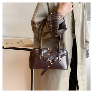 Detail of vintage dark brown oil wax leather shell bag with gold hardware and fashion embossing