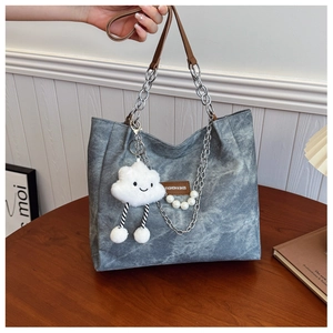 Detail of grey tote with silver chain strap, leather tag, and cute cloud charm accessory