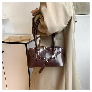Close-up of a vintage dark brown leather shoulder bag on a model wearing a beige trench coat