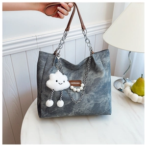 Detail of gray canvas tote with leather straps, pearl chain and cloud plush charm decoration