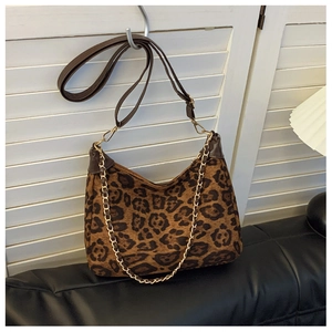 Detail of leopard print hobo bag with gold chain and brown leather trim on white door