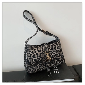 Close-up of leopard print shoulder bag featuring a gold spring hook buckle on a fabric texture