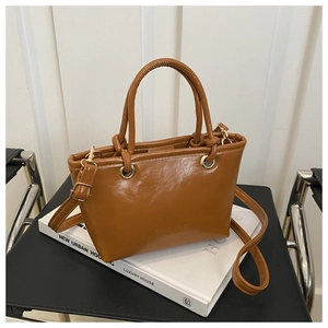 Detail der braunen Eimer-Tasche aus PU-Leder mit goldener Hardware und feiner Narbung