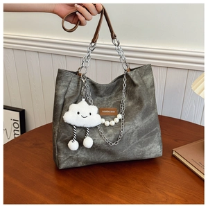 Detail of vintage gray canvas tote with silver chain strap and plush cloud charm