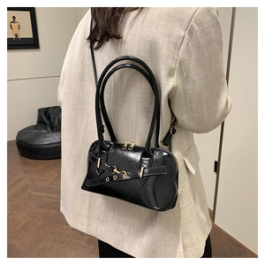 Detailed view of black patent leather bag with gold buckle and fashion strap design