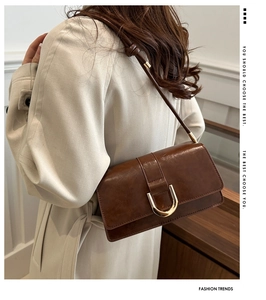 Sac à bandoulière en cuir marron avec boucle dorée porté en sac croisé par un mannequin