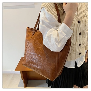 Close-up of brown crocodile pattern faux leather tote bag worn on shoulder
