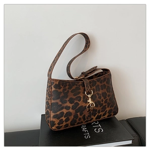 Close-up of leopard print hobo bag with a gold piston lock resting on a black book